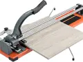 Tagliare piastrelle a mano con un tagliapiastrelle manuale. La piastrella chiara è pronta per essere tagliata con precisione.