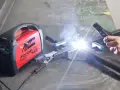 Saldare fili sottili con una saldatrice Telwin Force 145. Scintille luminose e fumo si alzano mentre un artigiano lavora.