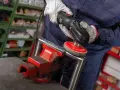 Operaio usa una lucidatrice con dischi abrasivi, parte dei prodotti per lucidare l'acciaio, per rifinire un pezzo metallico fissato in una morsa.