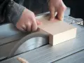 Mani esperte guidano un pezzo di legno su una sega circolare per tagliare legno a mano con precisione.