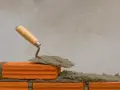 Una cazzuola con la malta pronta per costruire un muro. La malta a cosa serve? A tenere insieme i mattoni, creando strutture solide.