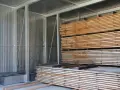 Legno impilato in un capannone, pronto per stagionare. Un progetto fai-da-te per conservare il legno.