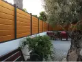 Pannello in legno effetto teak fissato a un muro bianco, con un ulivo secolare e arredi da esterno. Ideale per capire come fissare un pannello di legno al muro.