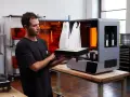 Uomo osserva due modelli architettonici bianchi appena stampati in 3D, pronti per essere rimossi dalla stampante.