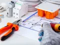 Schema elettrico con componenti per la messa a terra impianto elettrico: pinza, cacciavite, interruttori, scatola, lampadina e cavi.