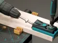 Attrezzo per guidare il trapano su un pezzo di legno, con morsetto e guida per fori precisi.