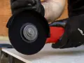 Mani guantate usano una smerigliatrice angolare per mostrare come tagliare le piastrelle con precisione.