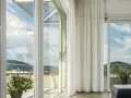 Ampie vetrate con vetro temperato significato di sicurezza e luminosità, con vista su un paesaggio collinare.
