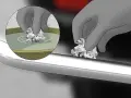 Guanto grigio immerge carta stagnola in acqua per rimuovere la ruggine dall'acciaio cromato.