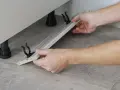 Mani che assemblano uno zoccolo cucina in alluminio, mostrando come tagliare e fissare i supporti.