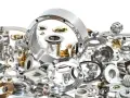 Una collezione di componenti metallici di precisione, alcuni lucidi, altri dorati. La loro accuratezza dimensionale è misurata in cosa sono i micron, essenziali per l'ingegneria moderna.