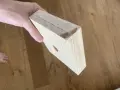 Mano che tiene un pezzo di legno con segni di matita, come se si stesse pensando a come tagliare il legno senza attrezzi.