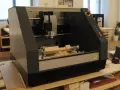 Macchina CNC in azione, che mostra come fresare il legno con trapano, creando trucioli di legno.