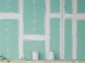 Pareti in cartongesso in fase di finitura, con stuccatura delle giunzioni. Si nota lo spessore delle pareti in cartongesso e due secchi di vernice.
