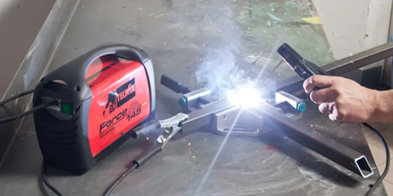 Saldare fili sottili con una saldatrice Telwin Force 145. Scintille luminose e fumo si alzano mentre un artigiano lavora.