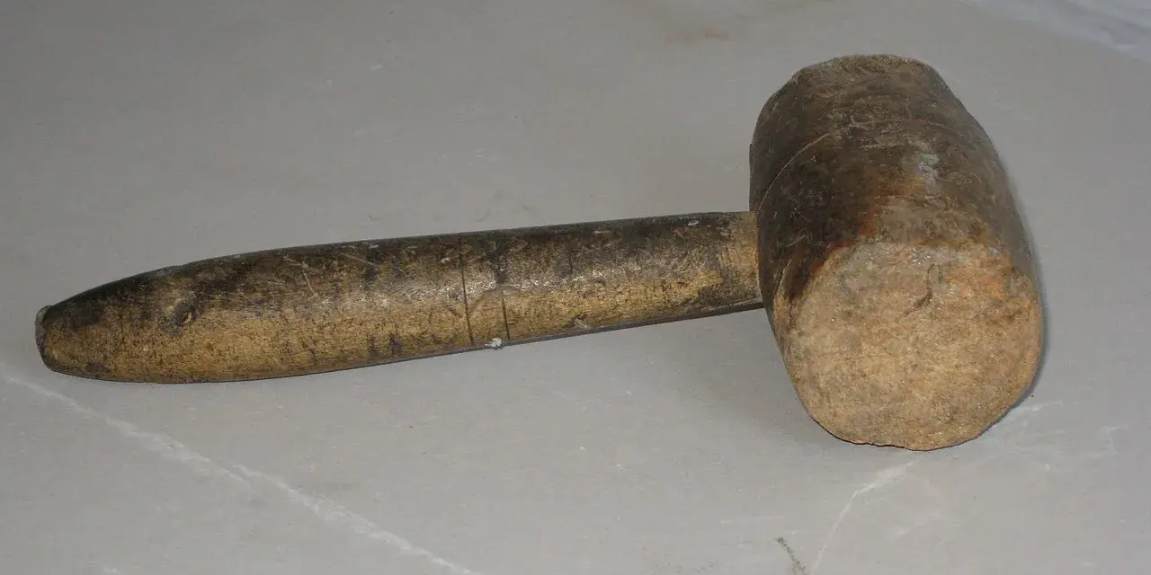 Un vecchio mazzuolo di legno, strumento che evoca il suo significato di forza e lavoro manuale.
