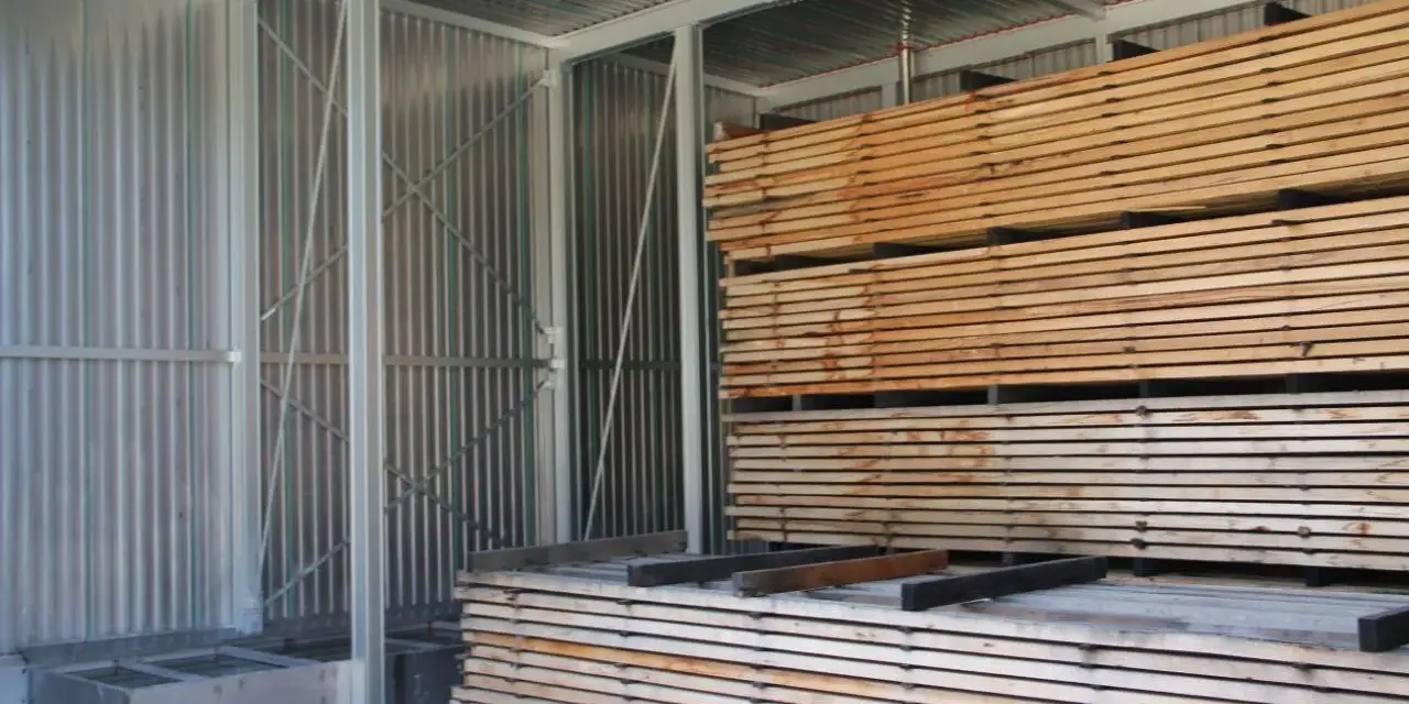 Legno impilato in un capannone, pronto per stagionare. Un progetto fai-da-te per conservare il legno.