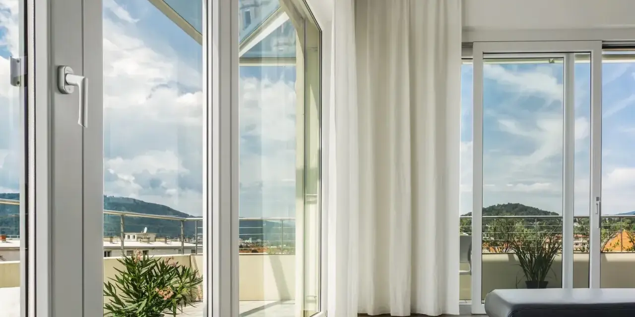 Ampie vetrate con vetro temperato significato di sicurezza e luminosità, con vista su un paesaggio collinare.