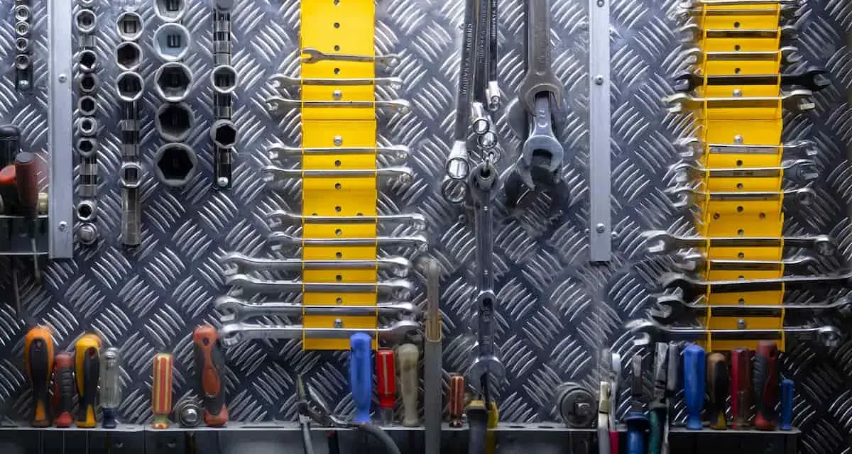 Organizzare officina: chiavi inglesi, bussole e cacciaviti ordinati su pannello metallico. Tutto a portata di mano per ogni lavoro.