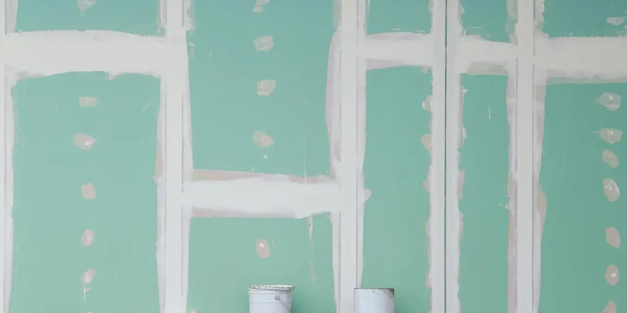 Pareti in cartongesso in fase di finitura, con stuccatura delle giunzioni. Si nota lo spessore delle pareti in cartongesso e due secchi di vernice.