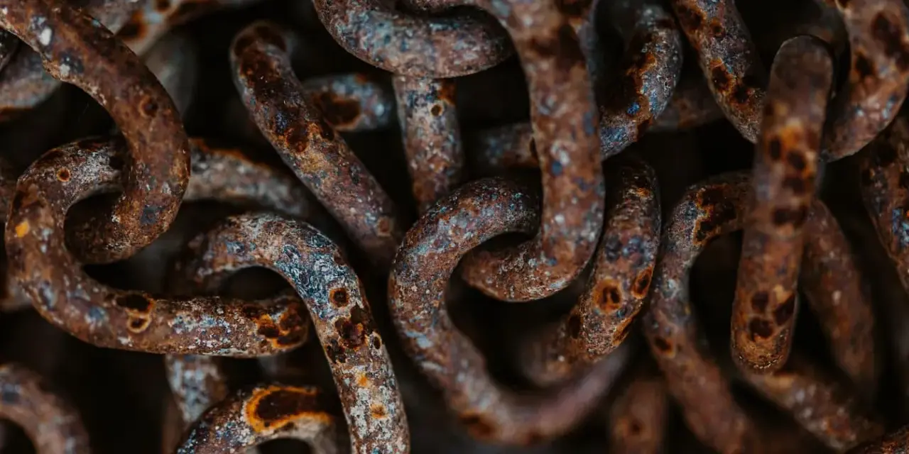 Dettaglio di una catena di ferro arrugginita, con macchie di ossido marrone e grigio. Utile per capire come togliere la ruggine da una catena di ferro.
