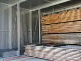 Legno impilato in un capannone, pronto per stagionare. Un progetto fai-da-te per conservare il legno.