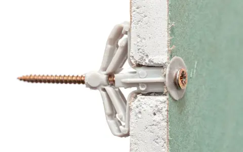 Un tassello Fisher e una vite inseriti in un muro di cartongesso. Illustra come mettere fisher nel muro per un fissaggio sicuro.