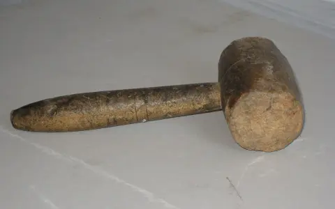 Un vecchio mazzuolo di legno, strumento che evoca il suo significato di forza e lavoro manuale.