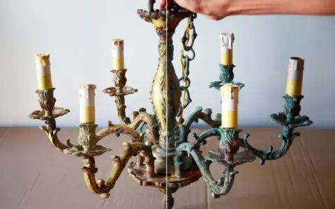 Prima e dopo: un lampadario in ottone con candele finte, mostra come pulire l'ottone con il bicarbonato per rimuovere l'ossidazione.