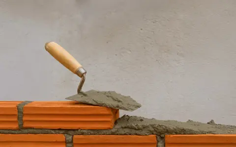 Una cazzuola con la malta pronta per costruire un muro. La malta a cosa serve? A tenere insieme i mattoni, creando strutture solide.