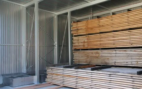 Legno impilato in un capannone, pronto per stagionare. Un progetto fai-da-te per conservare il legno.