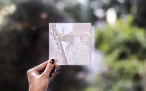 Litofania stampa 3d di Gandalf, tenuta in mano contro uno sfondo sfocato di alberi.