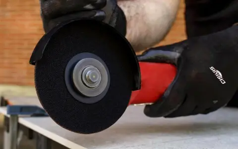 Mani guantate usano una smerigliatrice angolare per mostrare come tagliare le piastrelle con precisione.