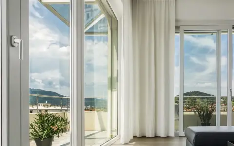 Ampie vetrate con vetro temperato significato di sicurezza e luminosità, con vista su un paesaggio collinare.