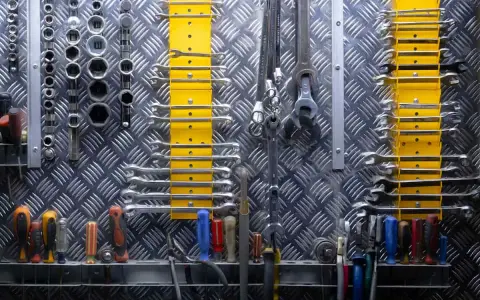 Organizzare officina: chiavi inglesi, bussole e cacciaviti ordinati su pannello metallico. Tutto a portata di mano per ogni lavoro.