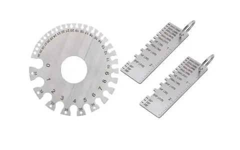 Strumenti di misurazione metallici, tra cui un disco graduato e due righelli, utili per determinare la portata di un calibro.