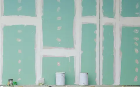 Pareti in cartongesso in fase di finitura, con stuccatura delle giunzioni. Si nota lo spessore delle pareti in cartongesso e due secchi di vernice.