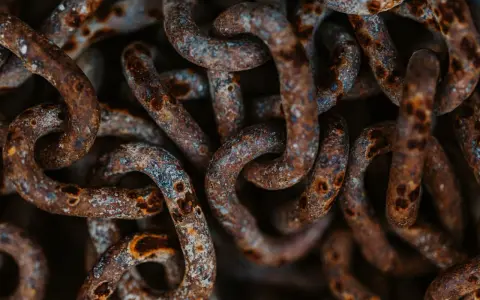Dettaglio di una catena di ferro arrugginita, con macchie di ossido marrone e grigio. Utile per capire come togliere la ruggine da una catena di ferro.