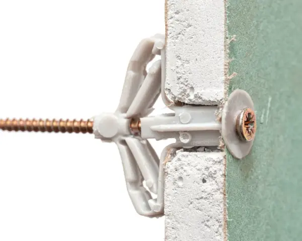 Un tassello Fisher e una vite inseriti in un muro di cartongesso. Illustra come mettere fisher nel muro per un fissaggio sicuro.