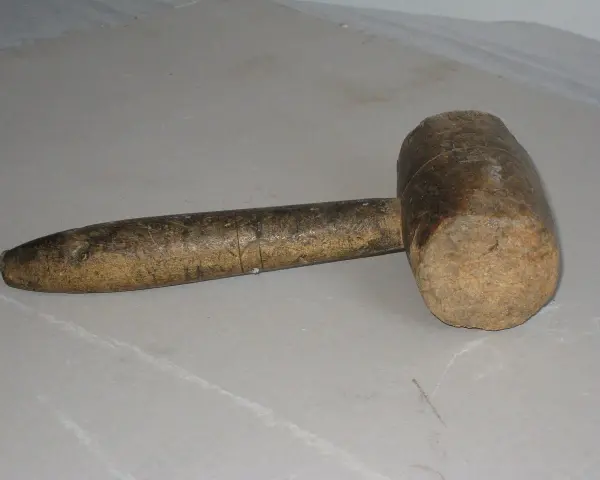 Un vecchio mazzuolo di legno, strumento che evoca il suo significato di forza e lavoro manuale.