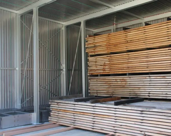 Legno impilato in un capannone, pronto per stagionare. Un progetto fai-da-te per conservare il legno.