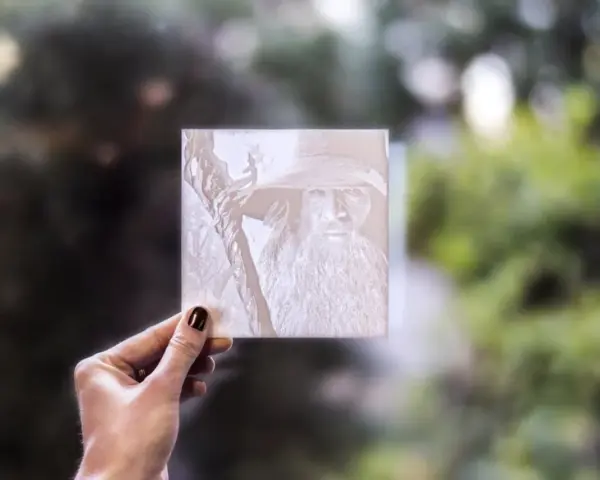 Litofania stampa 3d di Gandalf, tenuta in mano contro uno sfondo sfocato di alberi.