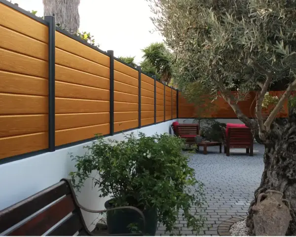 Pannello in legno effetto teak fissato a un muro bianco, con un ulivo secolare e arredi da esterno. Ideale per capire come fissare un pannello di legno al muro.