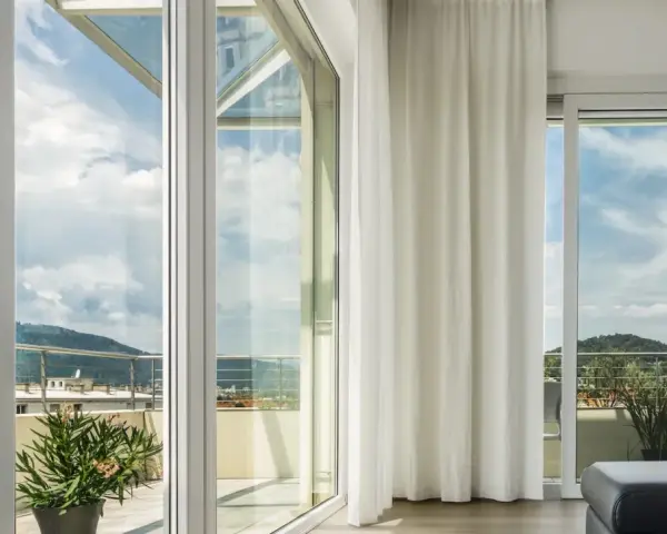 Ampie vetrate con vetro temperato significato di sicurezza e luminosità, con vista su un paesaggio collinare.