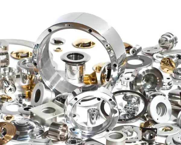 Una collezione di componenti metallici di precisione, alcuni lucidi, altri dorati. La loro accuratezza dimensionale è misurata in cosa sono i micron, essenziali per l'ingegneria moderna.