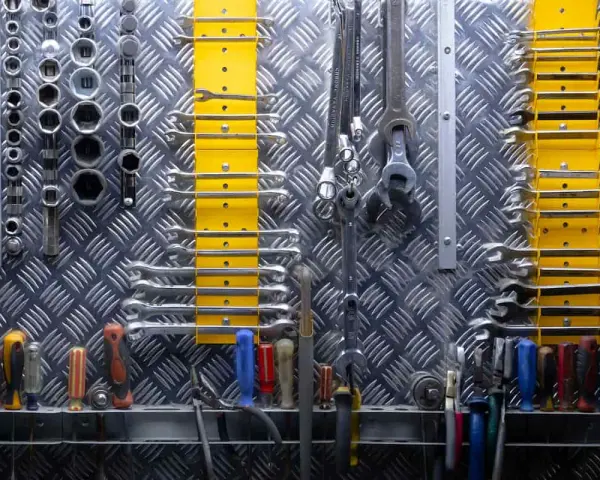 Organizzare officina: chiavi inglesi, bussole e cacciaviti ordinati su pannello metallico. Tutto a portata di mano per ogni lavoro.