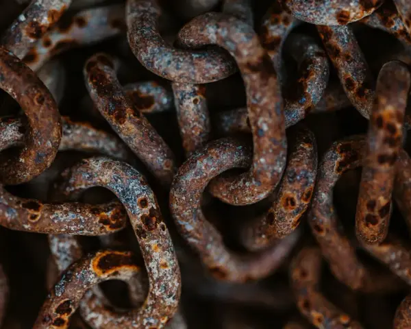 Dettaglio di una catena di ferro arrugginita, con macchie di ossido marrone e grigio. Utile per capire come togliere la ruggine da una catena di ferro.
