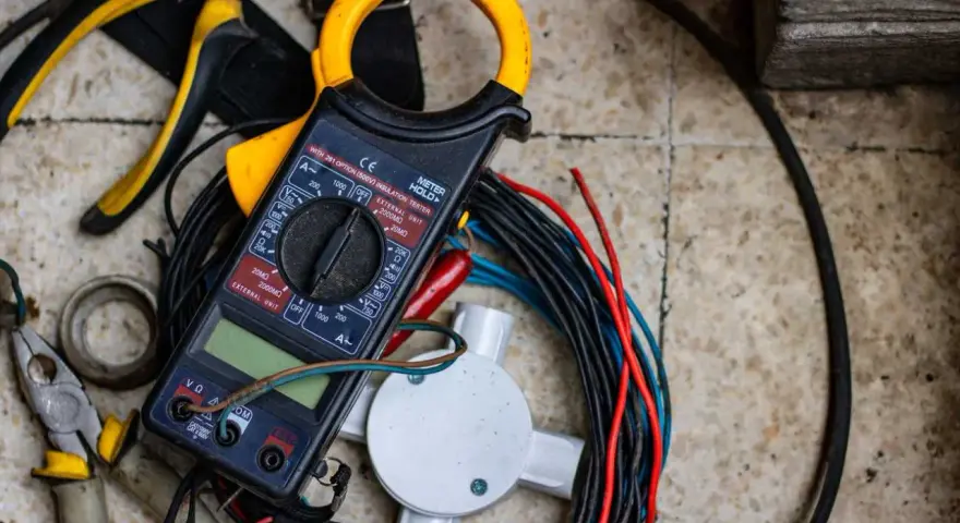 Strumenti elettrici, tra cui pinze e multimetro, pronti per imparare come spellare i cavi elettrici velocemente.
