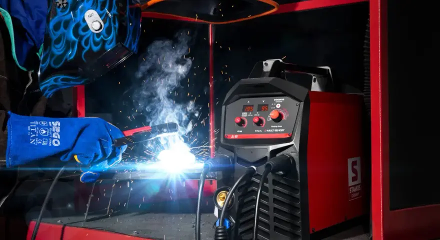Saldatore in azione, scintille luminose e fumo. La saldatrice Stamos S-MULTI 195 IGBT è pronta per l'uso. Guida per come scegliere una saldatrice.