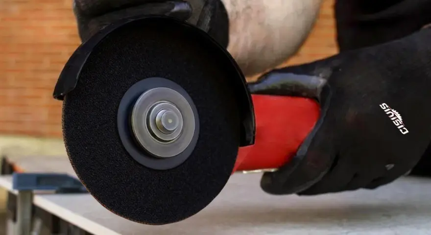 Mani guantate usano una smerigliatrice angolare per mostrare come tagliare le piastrelle con precisione.